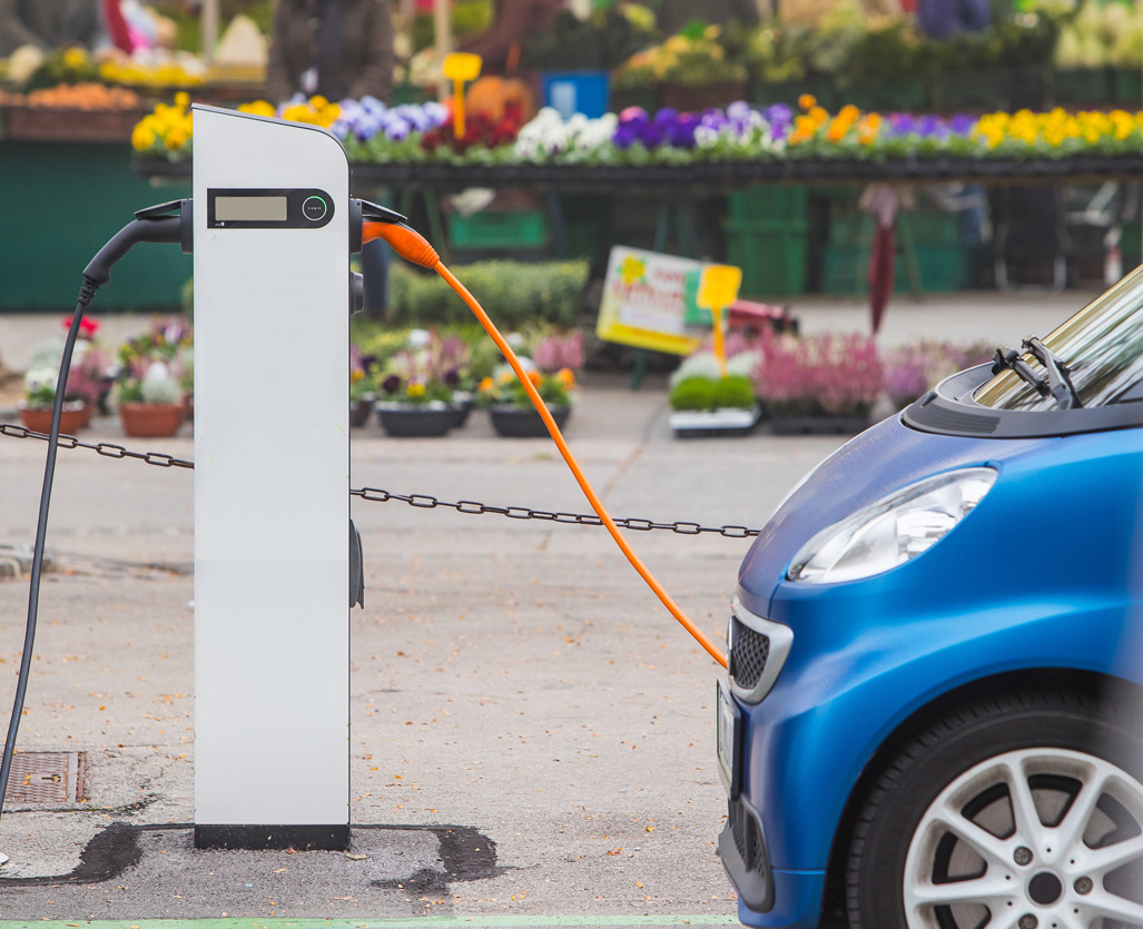 Car being recharged in front of flower stall